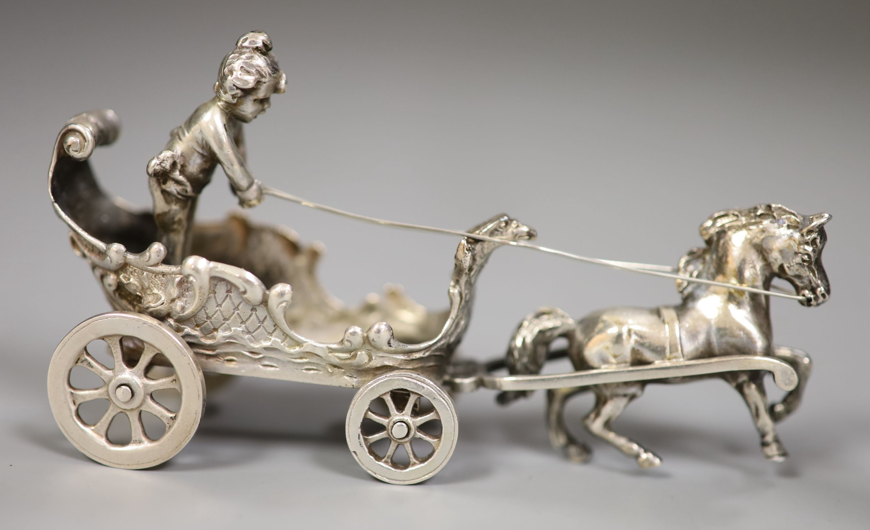 An early 20th century Continental white metal toy chariot, 10.3cm, a silver cherub on a chair and a silver Cupid desk seal
